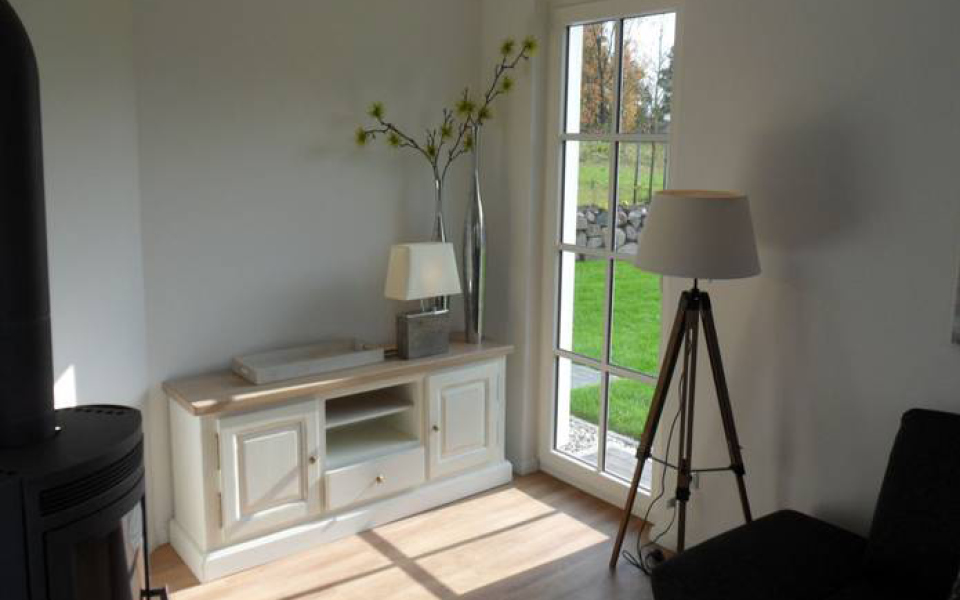 Wohnzimmer mit Kachelofen und weißem Sideboard aus Holz